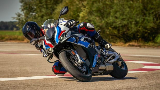 A BMW M 1000 RR motorcycle is taking a sharp turn on a racing track during the day, HD Desktop Wallpaper