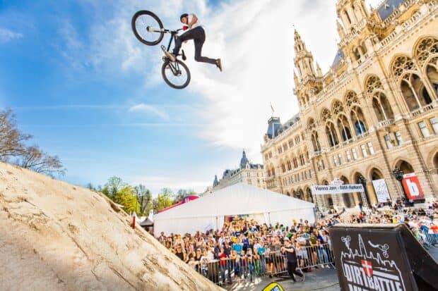 A BMX rider performs a mid air trick at a crowded urban BMX sports event, HD Desktop Wallpaper
