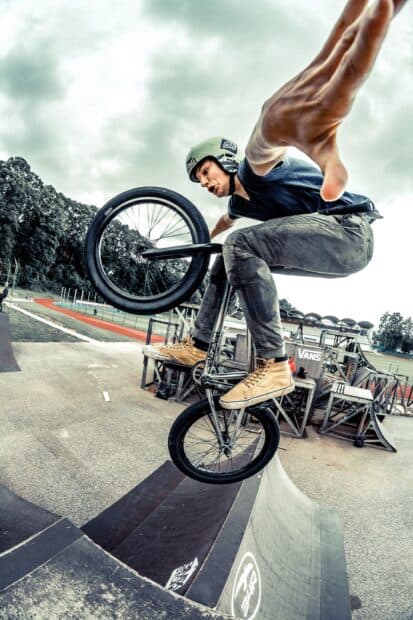 A BMX sports rider performs a trick in mid air at a skatepark ramp, 2K Mobile Wallpaper