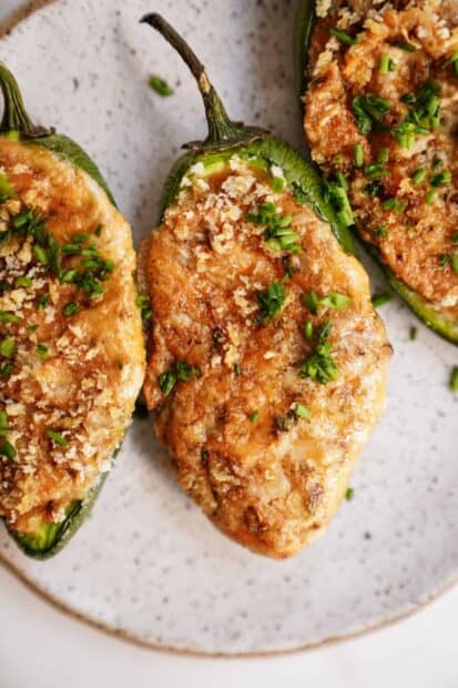 A close up view of baked jalapeno peppers filled with cheese and garnished with herbs, 2K Mobile Wallpaper