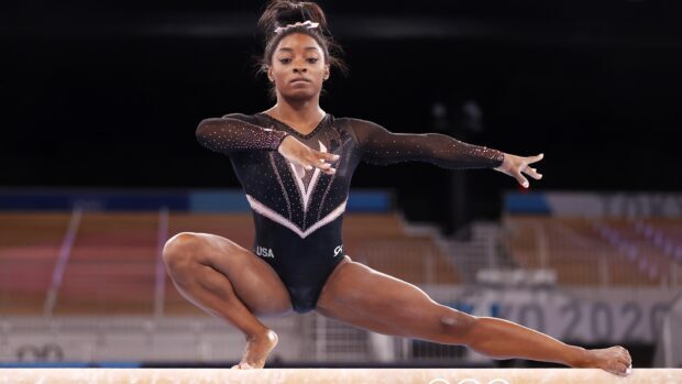 A gymnast demonstrates balance and strength on the balance beam during a competition, HD Desktop Wallpaper