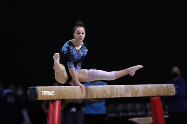 A gymnast demonstrates strength and balance on the balance beam during a competition, HD Desktop Wallpaper
