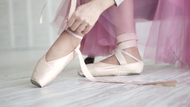 A ballet dancer is tying the ribbons of her pointe shoes while wearing a pink tutu, HD Desktop Wallpaper