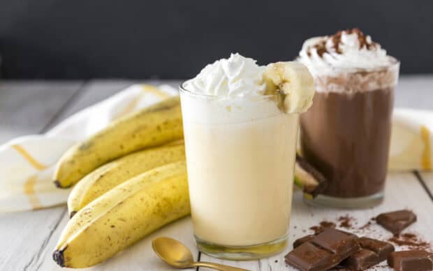 A glass of banana and chocolate milkshake topped with whipped cream and banana slice, 2K Desktop Wallpaper