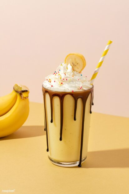 A banana milkshake topped with whipped cream and colorful sprinkles stands next to fresh bananas, HD Mobile Wallpaper