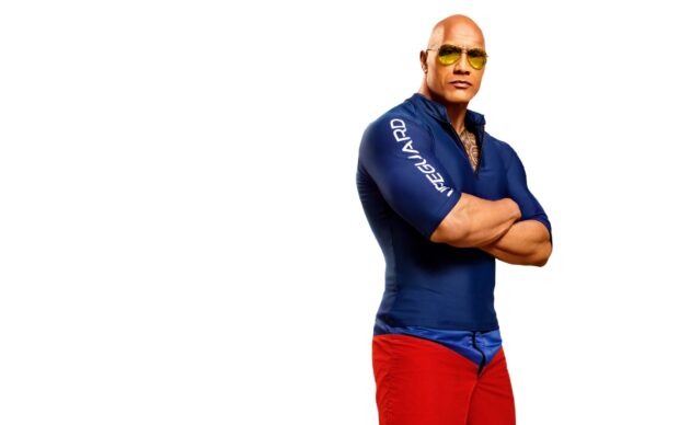A strong lifeguard stands confidently in Baywatch Movie Wallpapers, 2K Desktop Wallpaper