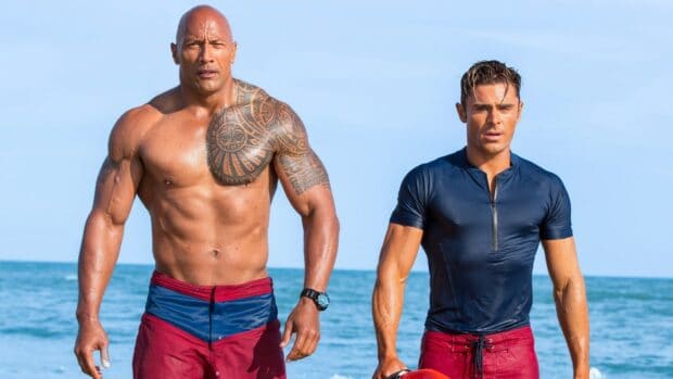 Two Baywatch movie characters in lifeguard outfits by the ocean, HD Desktop Wallpaper