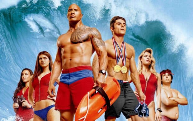 The Baywatch movie characters stand ready with ocean waves in the background, 2K Desktop Wallpaper