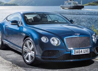 A blue Bentley Continental GT parked near a calm lake with a ferry in the background, 4K Desktop Wallpaper