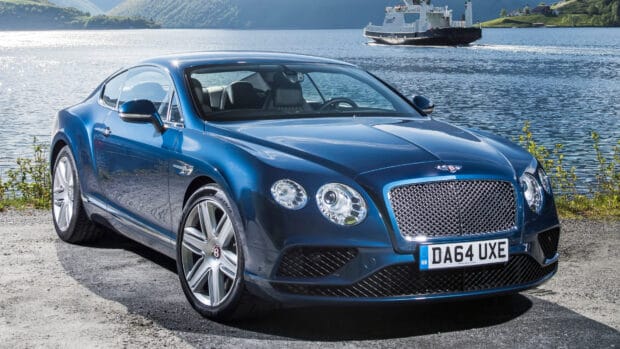 A blue Bentley Continental GT parked near a calm lake with a ferry in the background, 4K Desktop Wallpaper