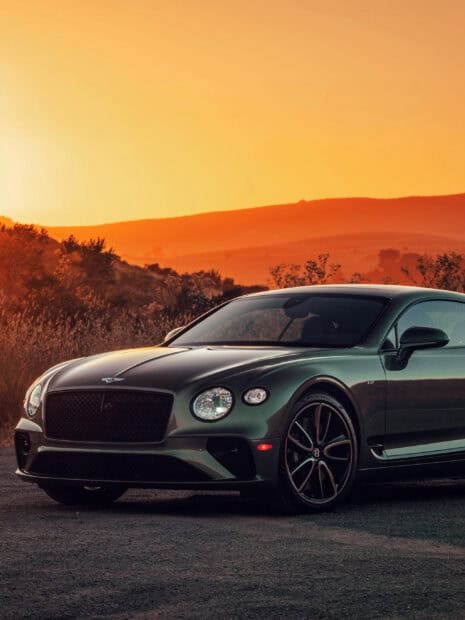 A luxurious Bentley Continental GT is parked on a rural road during sunset, 2K Phone Wallpaper