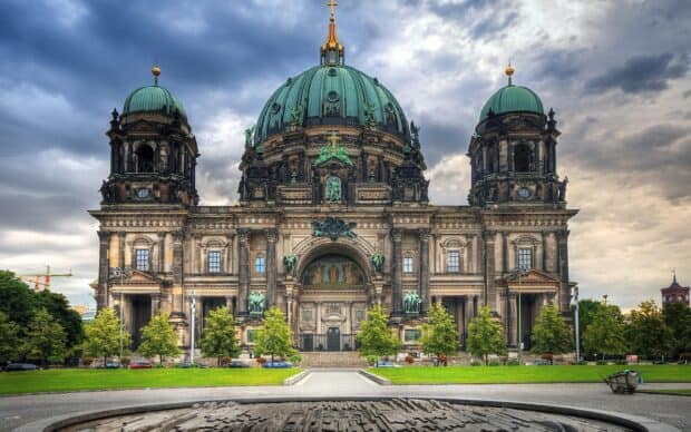 The Berlin Cathedral stands with its grand domes under a cloudy sky during the day, 2K Desktop Wallpaper