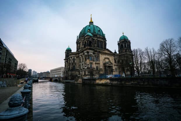Berlin Cathedral stands majestically beside the calm river at dusk, 2K Desktop Wallpaper