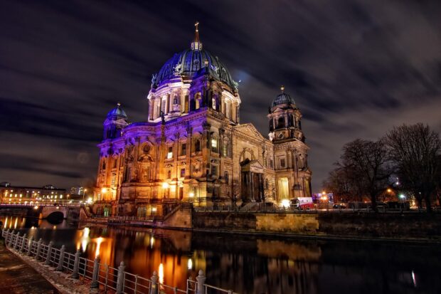Berlin Cathedral stands illuminated by warm lights under a cloudy night sky reflecting in the river, HD Desktop Wallpaper