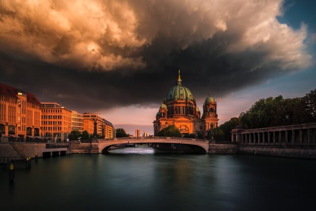 The Berlin Cathedral stands illuminated under a fiery sky by the river, HD Desktop Wallpaper