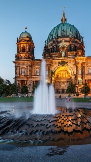 The Berlin Cathedral is illuminated near a water fountain in the evening, HD Mobile Wallpaper