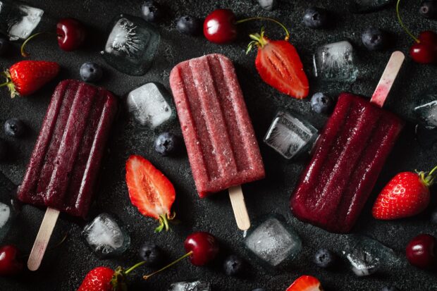 Three berry popsicles surrounded by strawberries cherries blueberries and ice cubes, 2K Desktop Wallpaper