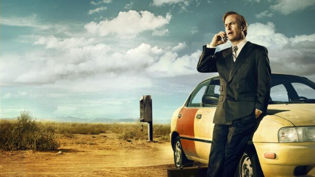 A man in a suit stands by an old car talking on the phone in a desert setting, HD Desktop Wallpaper