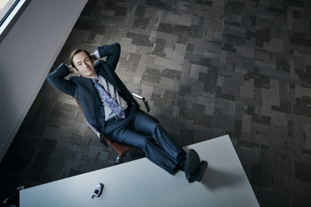 A man in a suit relaxes with his feet on the desk in an office setting, HD Desktop Wallpaper