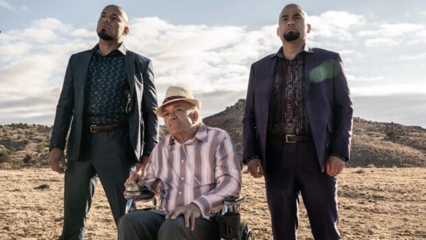 Three men stand in a desert landscape with one sitting in a wheelchair, HD Desktop Wallpaper
