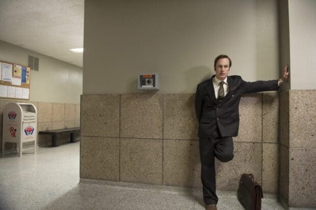 Better Call Saul standing in a hallway wearing a suit with a briefcase on the floor, 2K Desktop Wallpaper