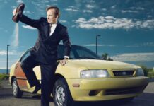 A man in a suit throwing sand from his shoe near a yellow car under a blue sky with clouds, HD Desktop Wallpaper