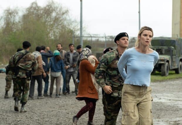 Betty Gilpin is held by a soldier while a group of people stands near a fence in the background, 2K Desktop Wallpaper