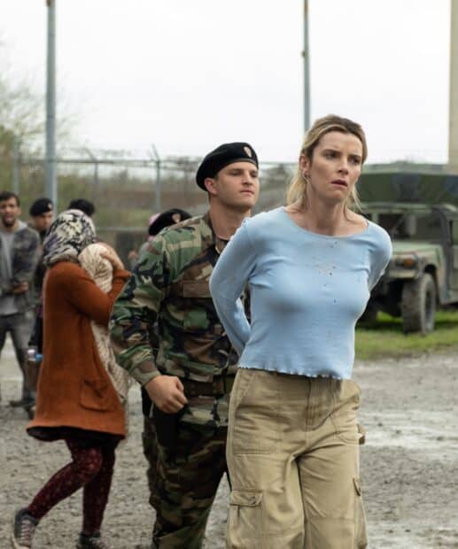 Betty Gilpin is handcuffed and guarded by a soldier in a tense outdoor setting, HD Desktop Wallpaper
