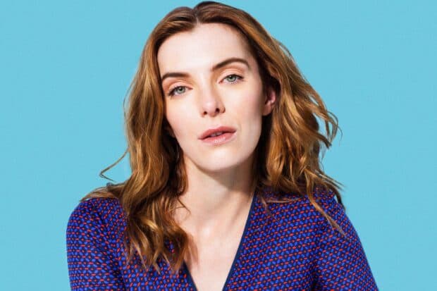 Betty Gilpin is posing against a blue backdrop in a patterned top, 2K Desktop Wallpaper