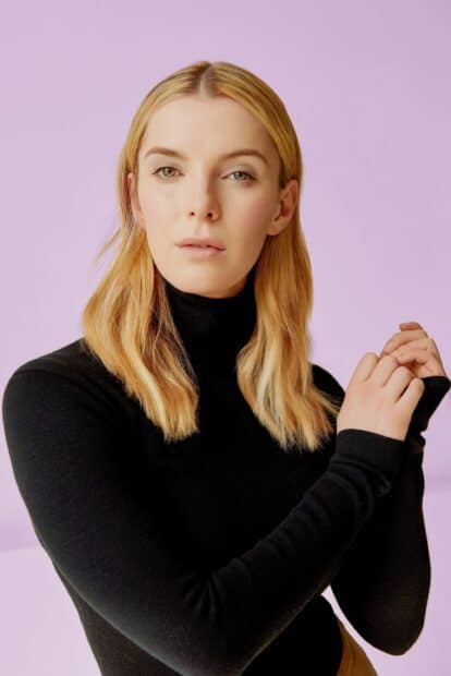 Betty Gilpin wears a black turtleneck and poses against a purple background, 2K Mobile Wallpaper