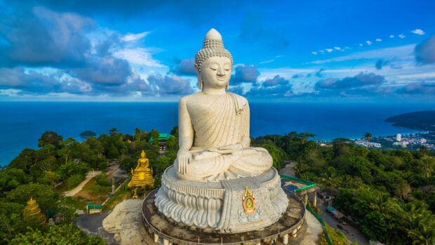 A giant Buddha statue overlooks the forest and ocean in Phuket with blue skies, HD Desktop Wallpaper