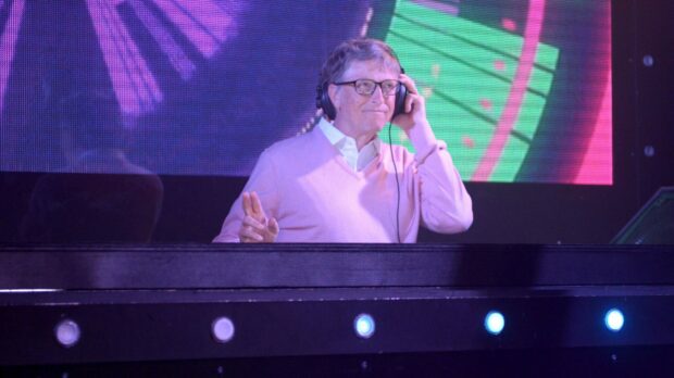 Bill Gates is wearing headphones and smiling during a colorful stage event, HD Desktop Wallpaper