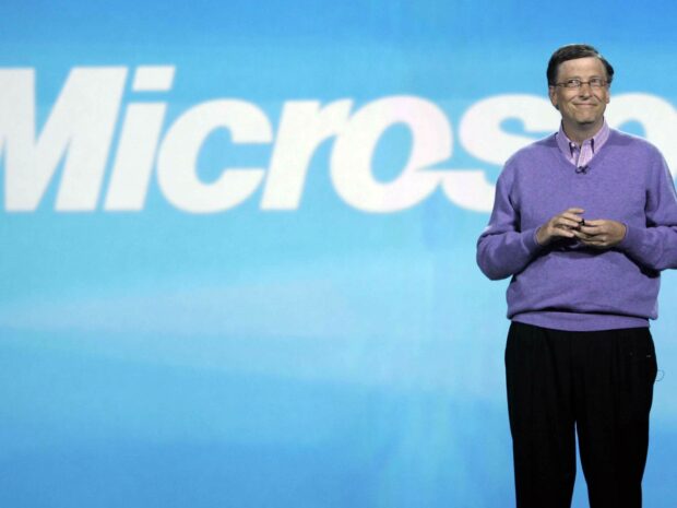 Bill Gates stands smiling with the Microsoft logo behind him, HD Desktop Wallpaper