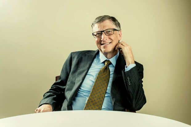 Bill Gates wallpapers shows him sitting at a table wearing a suit and glasses, HD Desktop Wallpaper