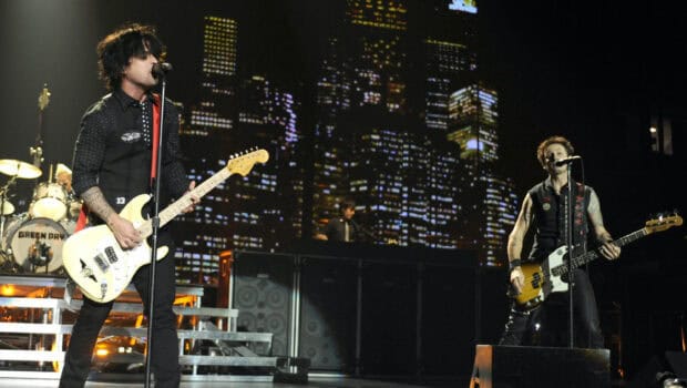Billie Joe Armstrong performing live on stage with the band in front of a cityscape backdrop, 2K Desktop Wallpaper