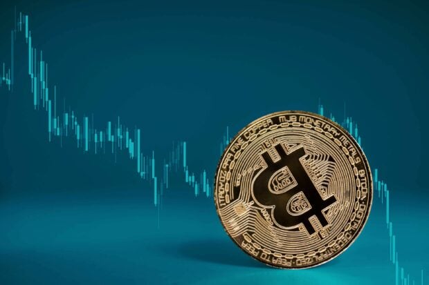 A golden Bitcoin coin stands before a declining price chart on a blue background, 2K Desktop Wallpaper