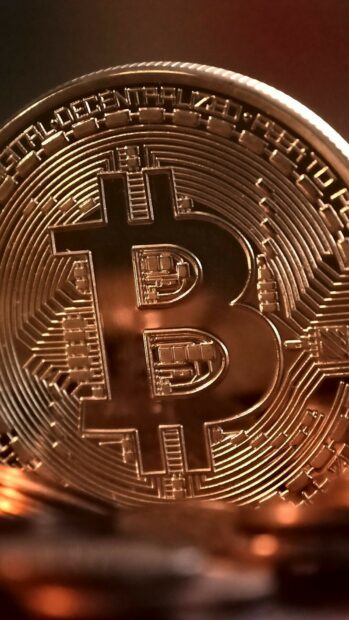 A detailed close up of a Bitcoin coin in warm lighting featuring the Bitcoin Wallpapers Collection, HD Phone Wallpaper