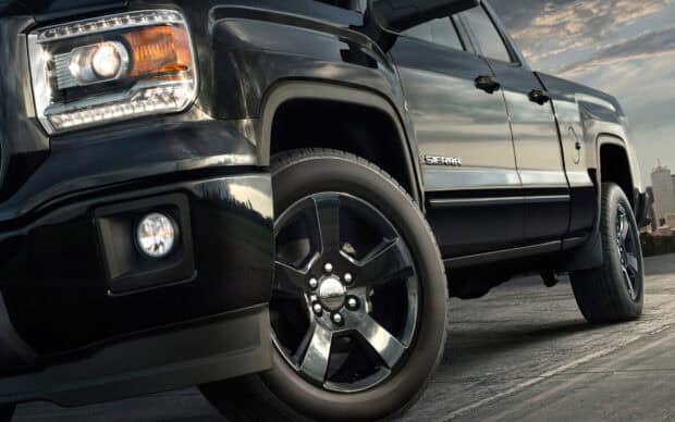 The black GMC Sierra pickup truck is parked on the road with city skyline in the background, HD Desktop Wallpaper