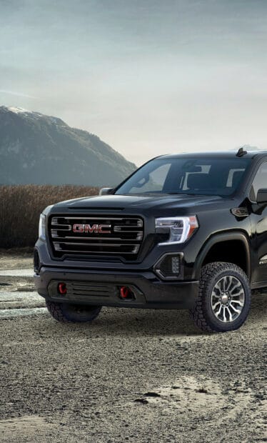 A black GMC Sierra is parked on rough ground with mountains in the background, HD Mobile Wallpaper