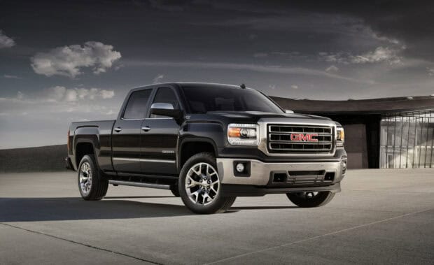 A black GMC Sierra is parked outside near a modern building under a cloudy sky, HD Desktop Wallpaper