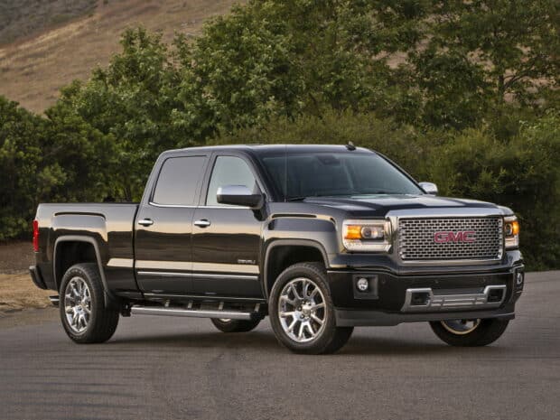 A black GMC Sierra truck is parked on an empty road near trees and hills, HD Desktop Wallpaper