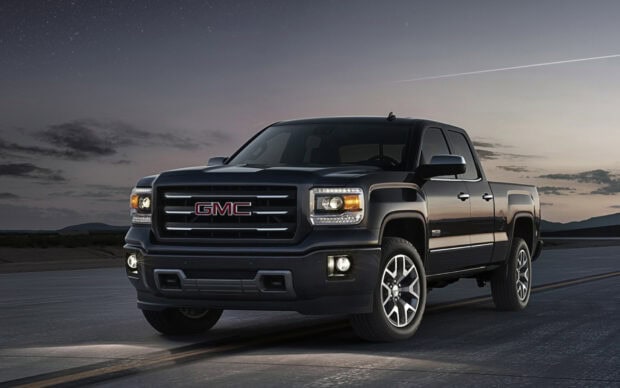 Black GMC Sierra truck is parked on a road during dusk with headlights on and a cloudy sky, HD Desktop Wallpaper