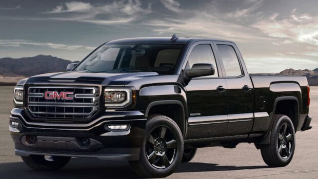 A black GMC Sierra truck is parked on a concrete surface with mountains in the background, 4K Desktop Wallpaper