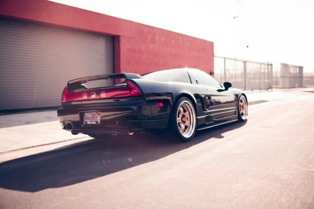 Black Honda NSX sports car parked near a red wall under bright sunlight, 2K Desktop Wallpaper