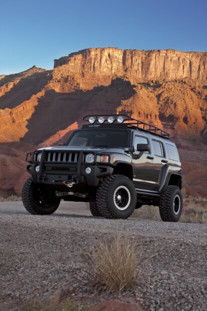 A black Hummer H3 is parked on rocky terrain with red cliffs in the background, 2K Mobile Wallpaper