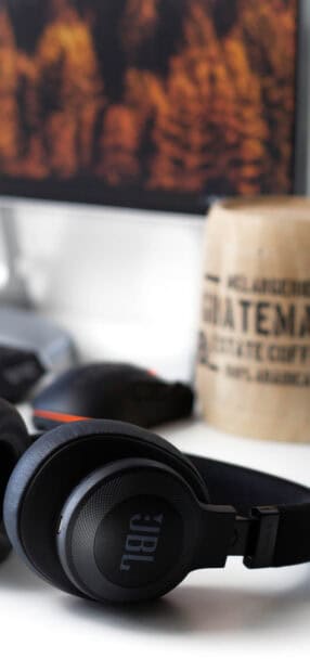 Black JBL headphones resting on a white desk near a coffee sack and computer mouse, 2K Mobile Wallpaper