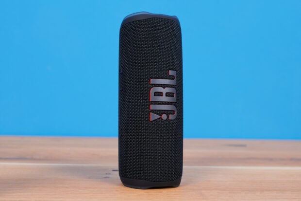 A black JBL speaker stands on a wooden surface with a clear blue background, 2K Desktop Wallpaper