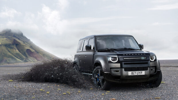 A black Land Rover Defender drives through rocky terrain near a mountain under a cloudy sky, 4K Desktop Wallpaper