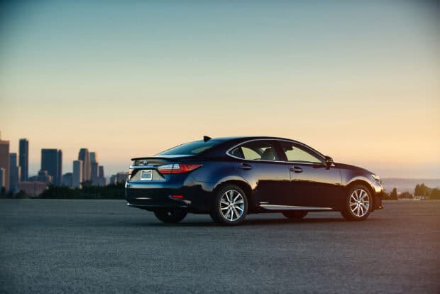 A black Lexus Es is parked with a city skyline visible at sunset, 2K Desktop Wallpaper