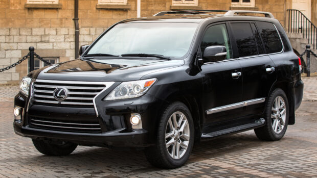 A black Lexus LX SUV is parked on a cobblestone street near a stone wall, 4K Desktop Wallpaper